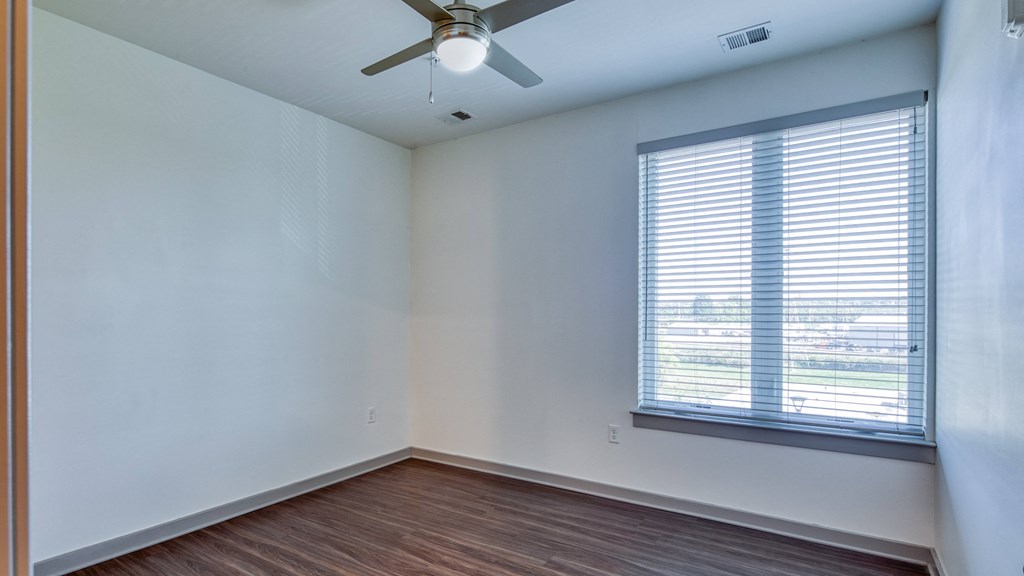 an empty room with a large window and a ceiling fan