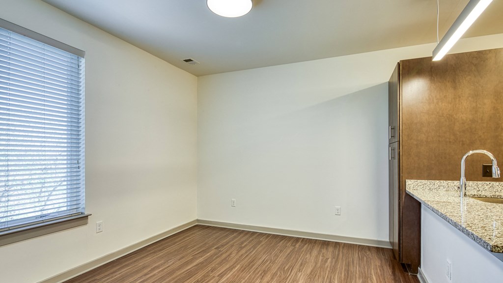 an empty living room with a kitchen and a large window