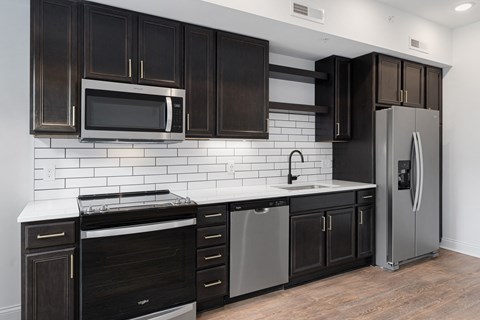 A kitchen with black cabinets and a white tile backsplash.