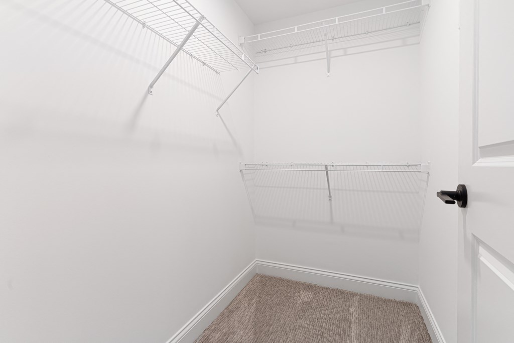 a walk in closet with white walls and white shelves and a white door at The Madison, Columbus, Ohio