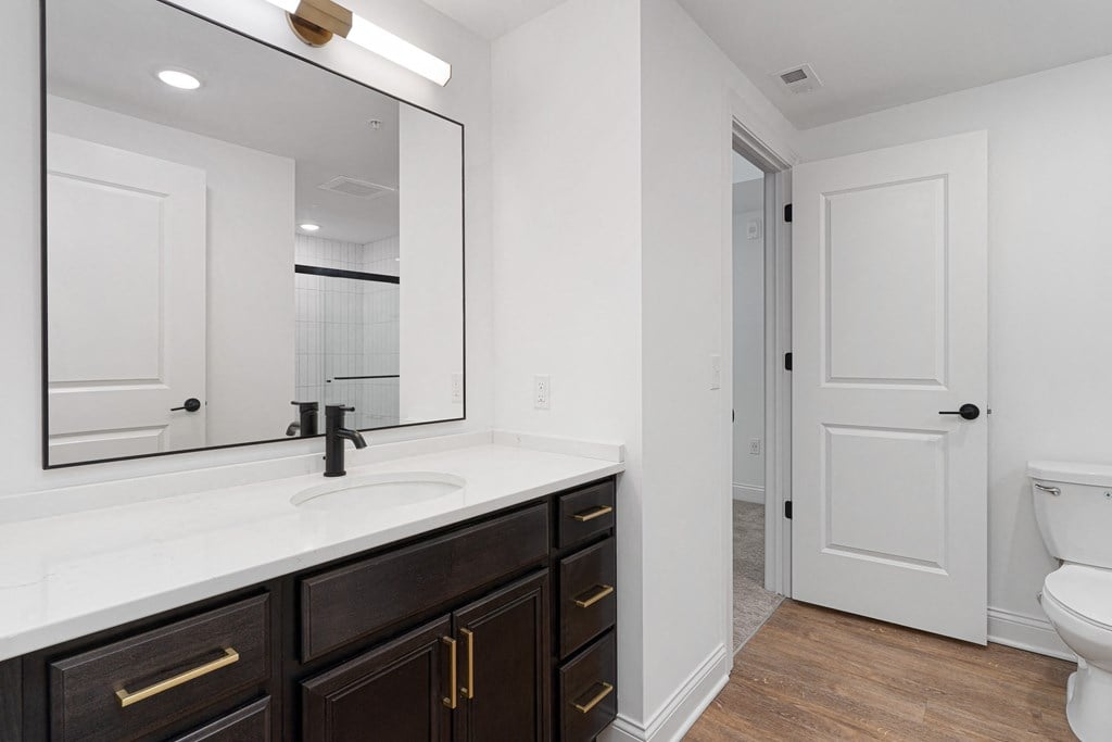 a bathroom with a large mirror and a sink and a toilet at The Madison, Columbus