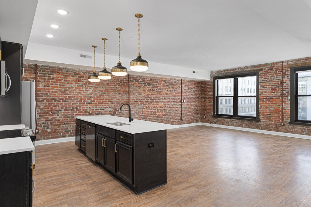 the kitchen has a large island with a sink and a brick wall at The Madison, Columbus, Ohio