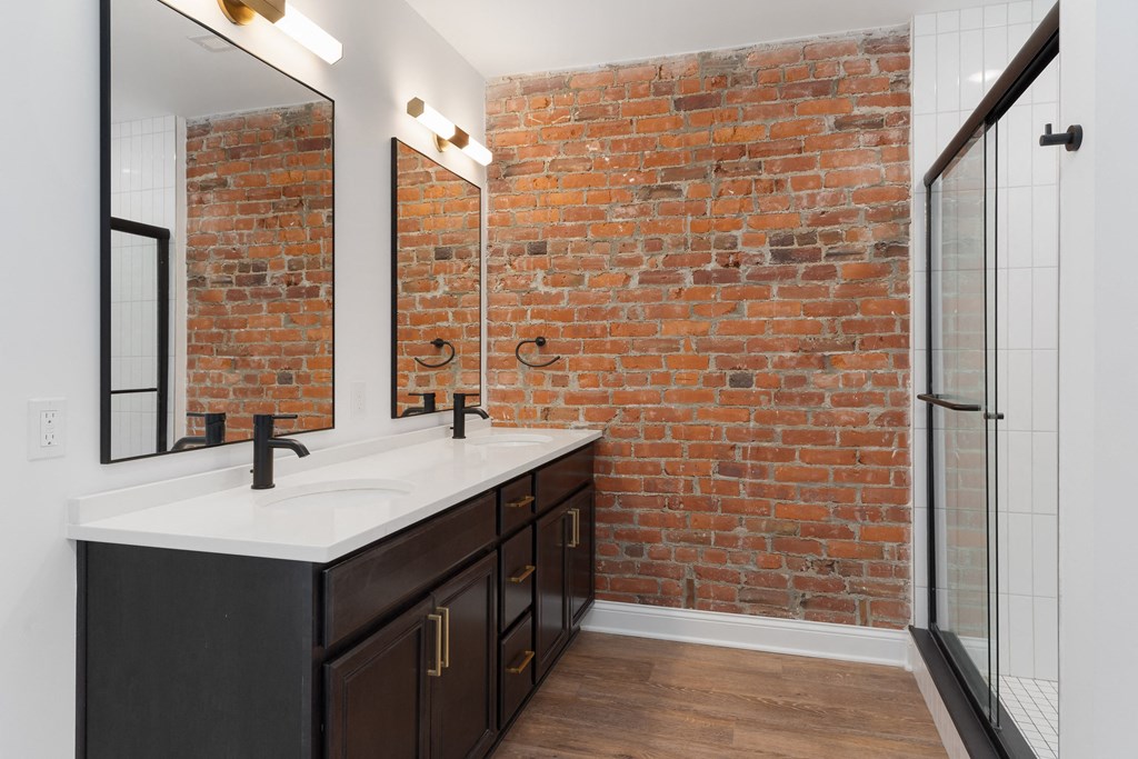 a bathroom with a brick wall and a sink and a mirror at The Madison, Columbus, OH, 43215