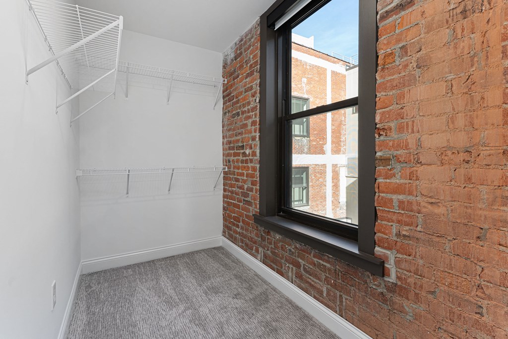 an empty room with a brick wall and a window at The Madison, Columbus, Ohio