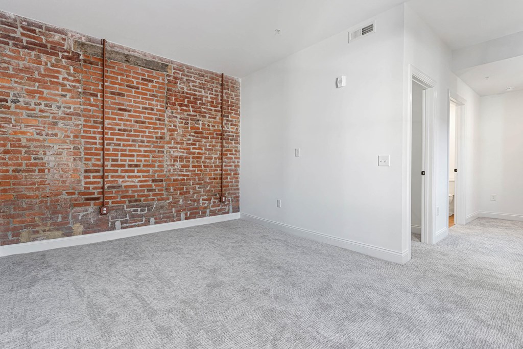 an empty room with a brick wall and white carpet at The Madison, Columbus