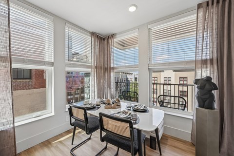 A dining room with a table set for two and a view of a balcony.