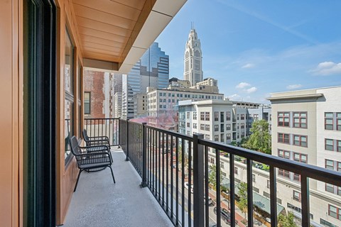 A balcony with chairs and a view of a city skyline.