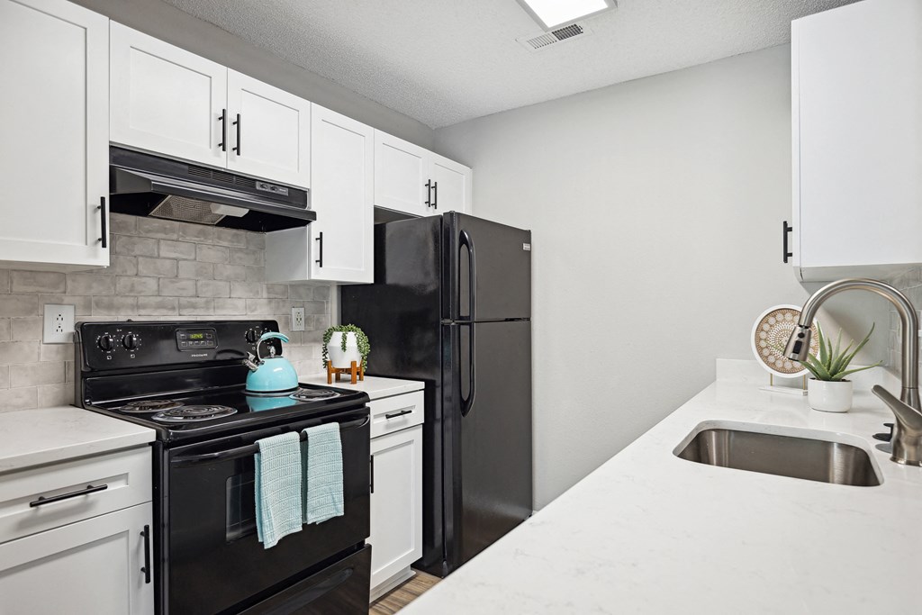 an apartment kitchen with black appliances and white cabinets