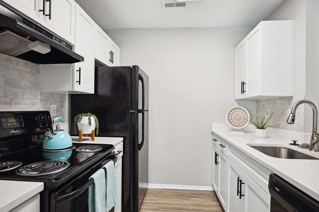 a kitchen with white cabinets and black appliances and a black refrigerator