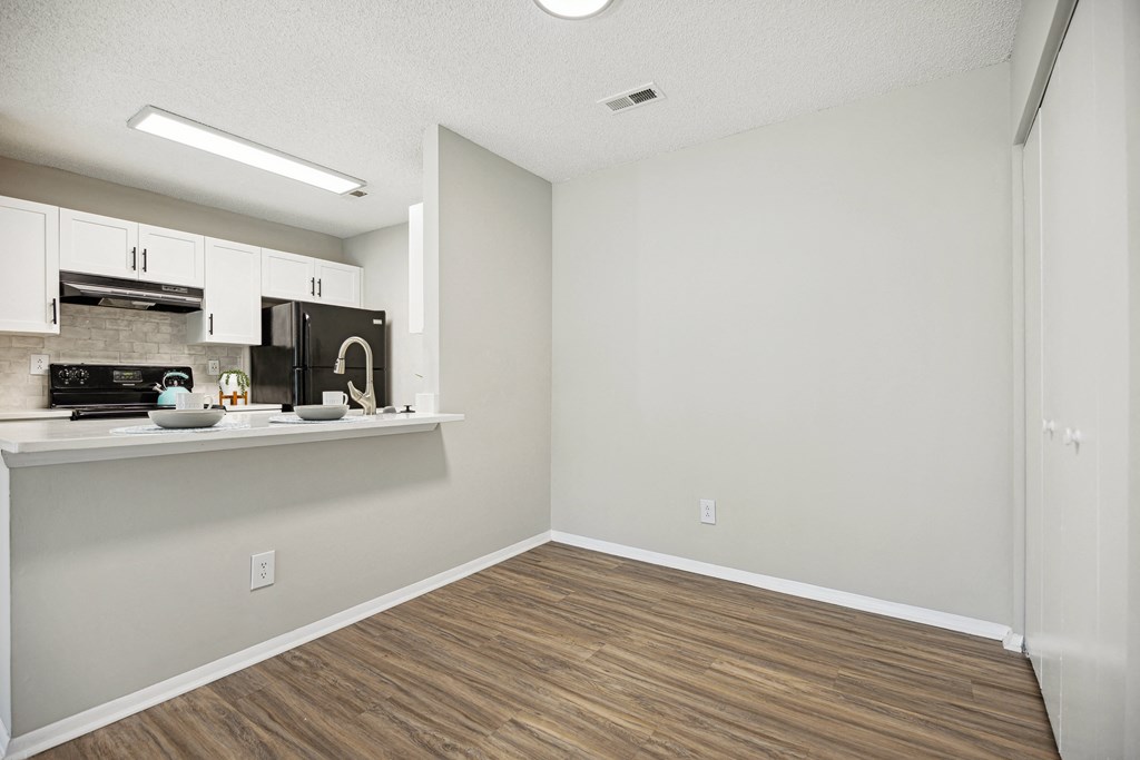 an empty kitchen and living room with white walls and wood flooring