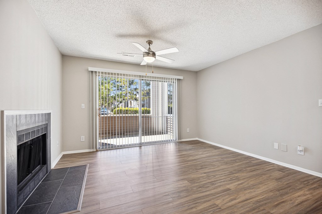 an empty living room with a fireplace and a ceiling fan