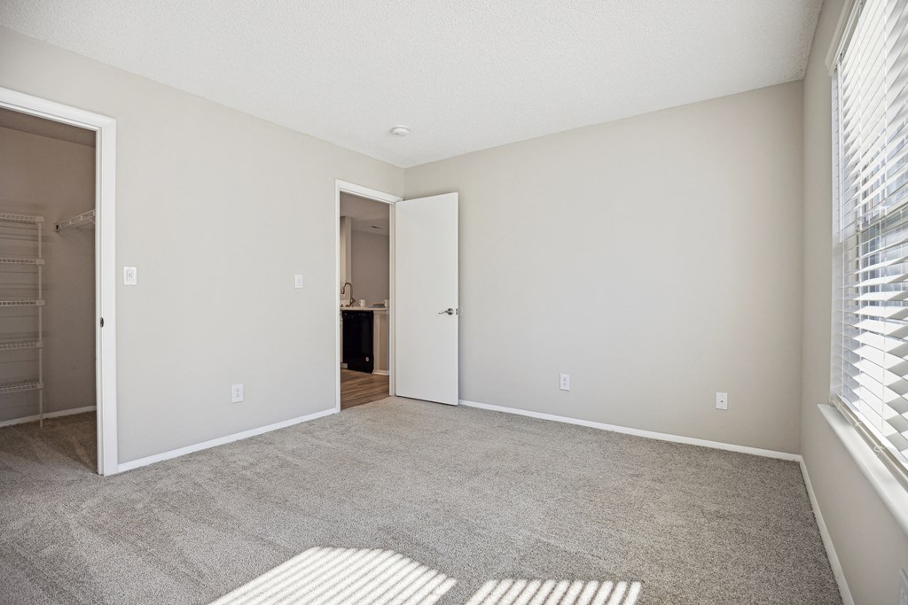 an empty living room with a large window and a door to a bathroom