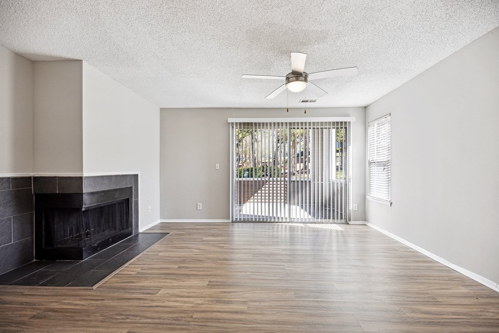 an empty living room with a fireplace and a ceiling fan