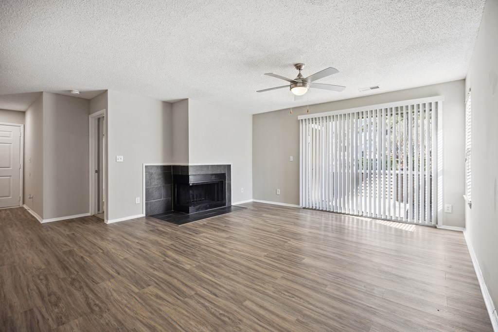 an empty living room with a fireplace and a ceiling fan
