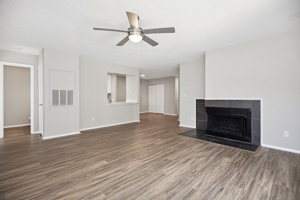 an empty living room with a fireplace and a ceiling fan
