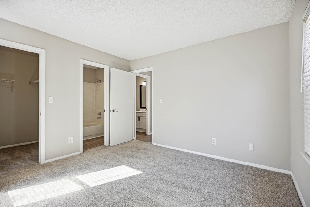 an empty living room with white walls and a door to a bathroom
