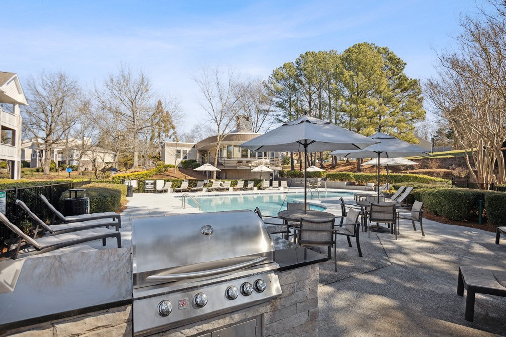 an outdoor patio with a pool and chairs and umbrellas
