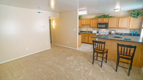 A kitchen with a counter and two chairs.