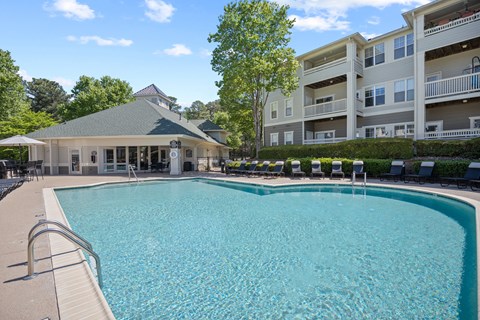 A large swimming pool with a diving board and a building in the background.