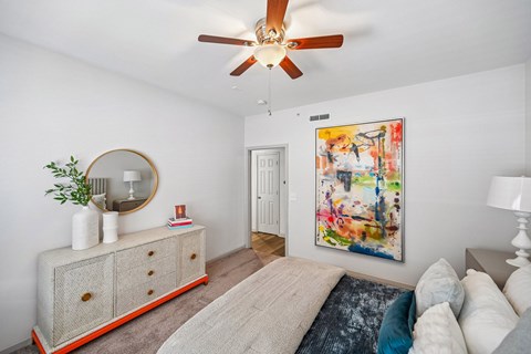 A room with a large painting on the wall and a red and white cabinet.