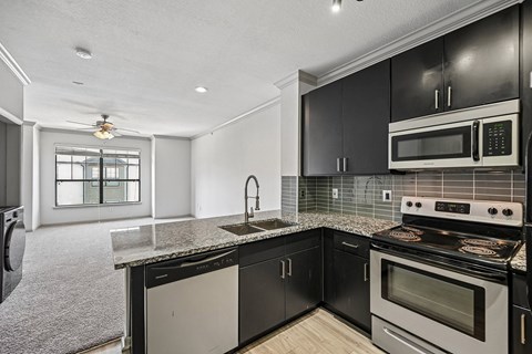 A modern kitchen with black cabinets and a white stove top oven.