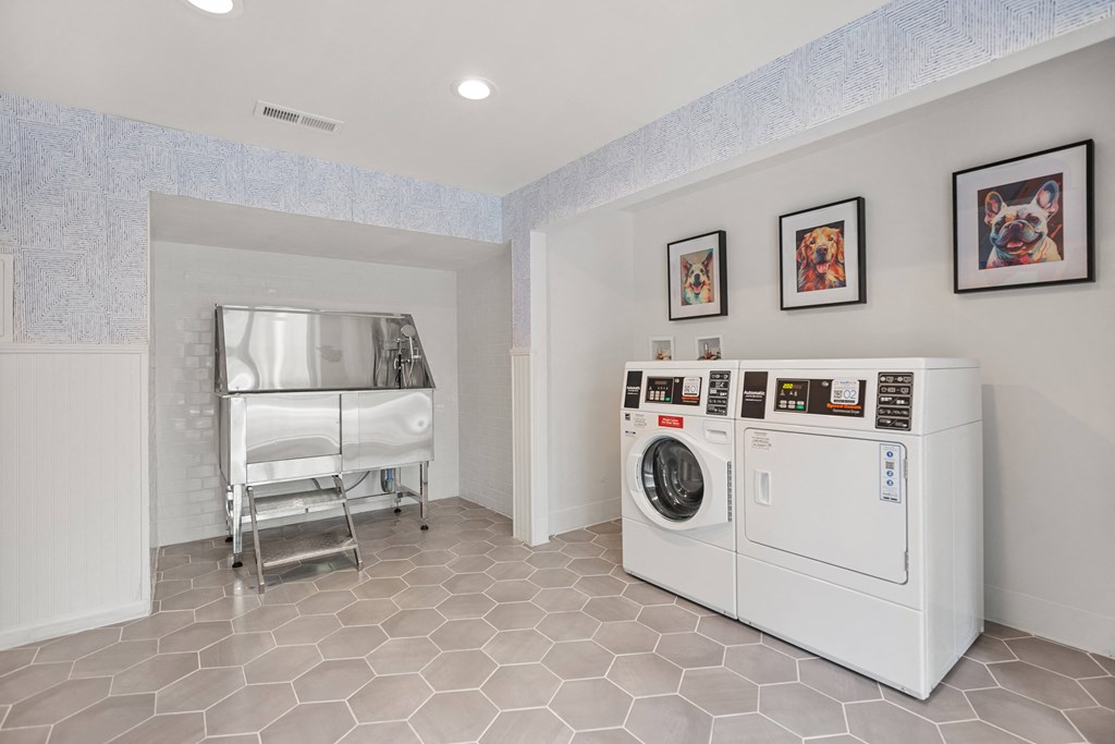 a laundry room with a washer and dryer and a bed in the corner