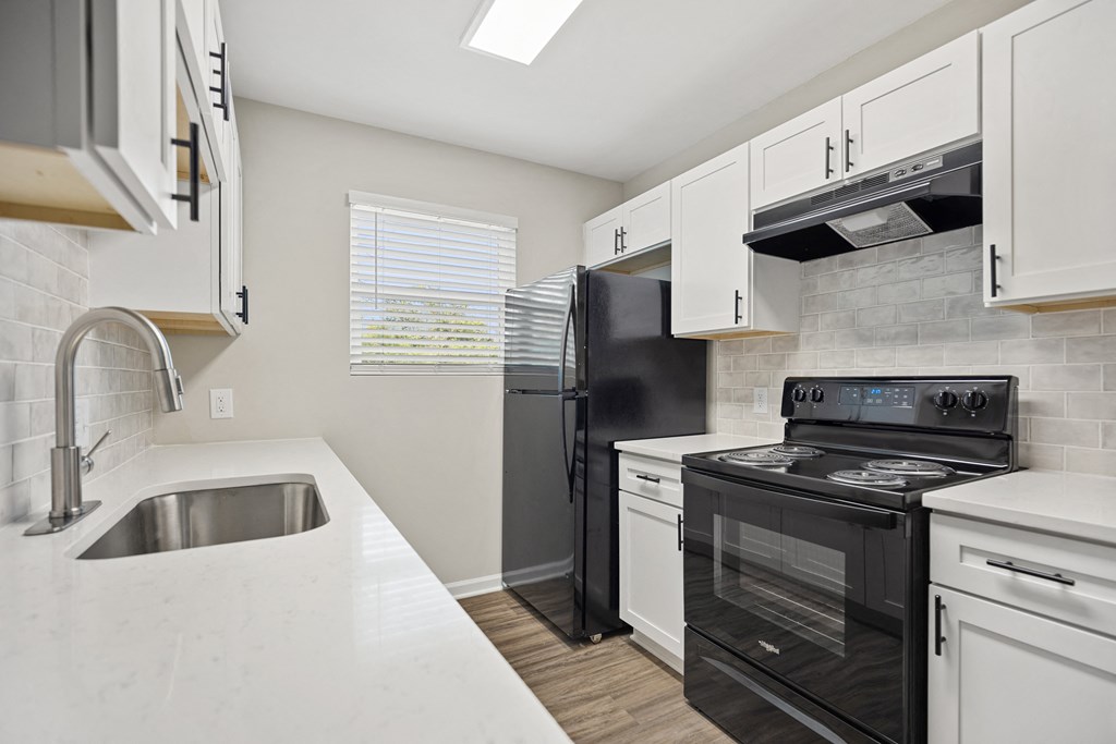 an empty kitchen with white cabinets and black appliances