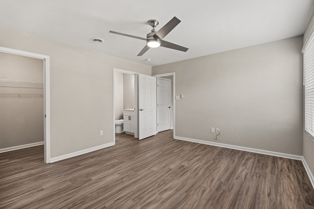 an empty living room with a ceiling fan and a bathroom