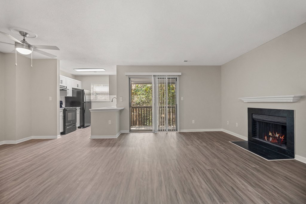 an empty living room with a fireplace and a kitchen