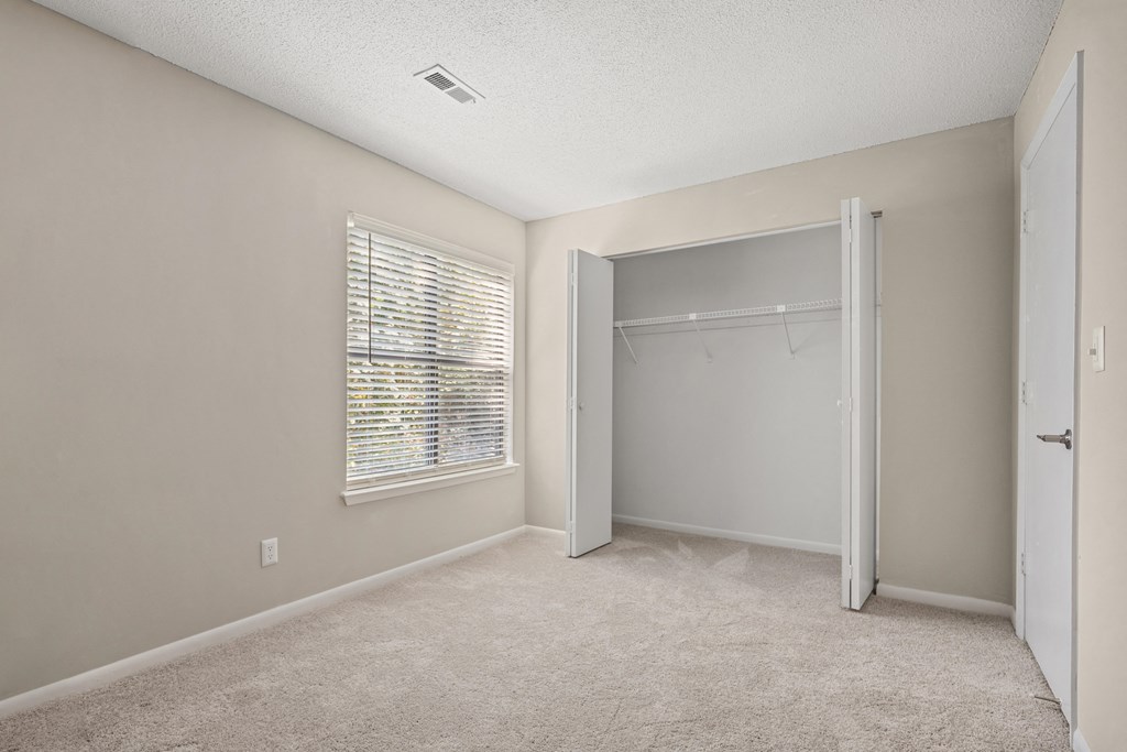 an empty bedroom with a closet and a window