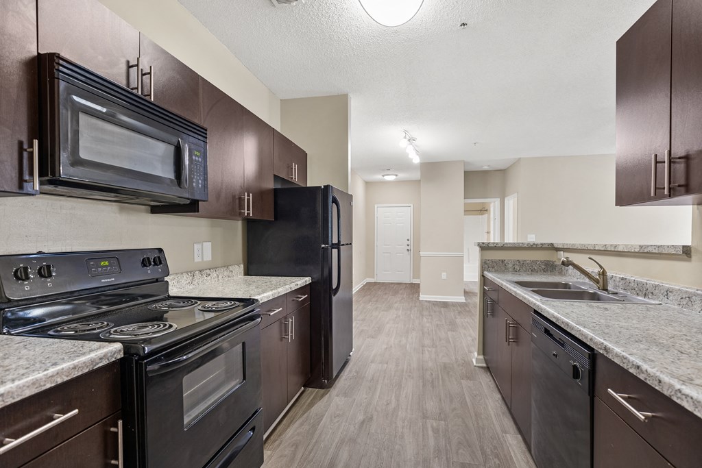 an empty kitchen with black appliances and granite counter tops