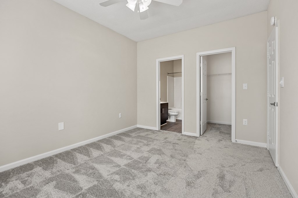 an empty living room with a ceiling fan and a door to a bathroom