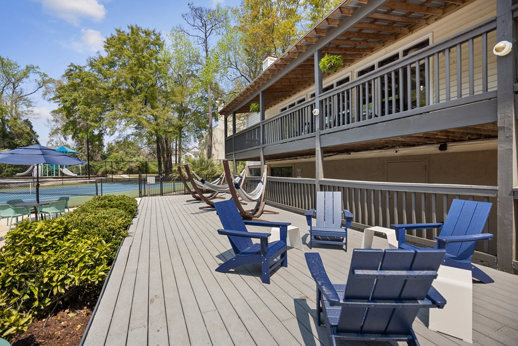 a deck with blue chairs and a house with a pool