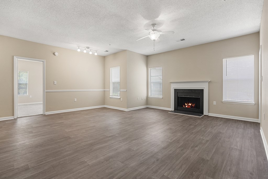 an empty living room with a fireplace and a ceiling fan