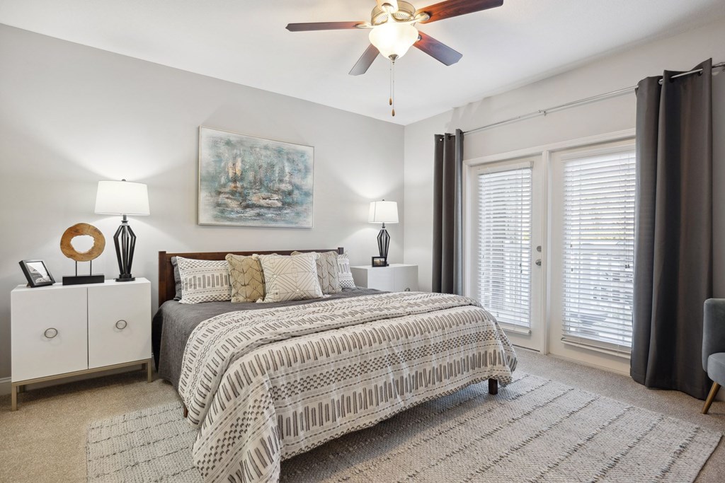 A bedroom with a large bed and a ceiling fan.
