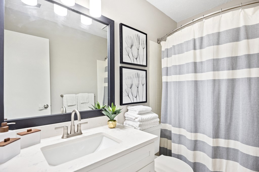 a bathroom with a large mirror and a striped shower curtain