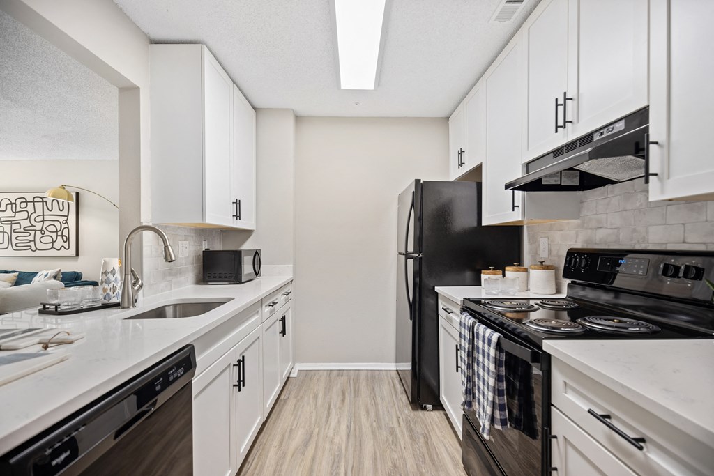 an apartment kitchen with white cabinets and black appliances and a stove and refrigerator
