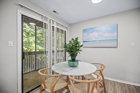 a dining area with a table and chairs and a door to a balcony