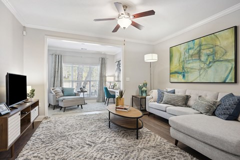 A living room with a grey couch, a coffee table, a television, and a painting on the wall.