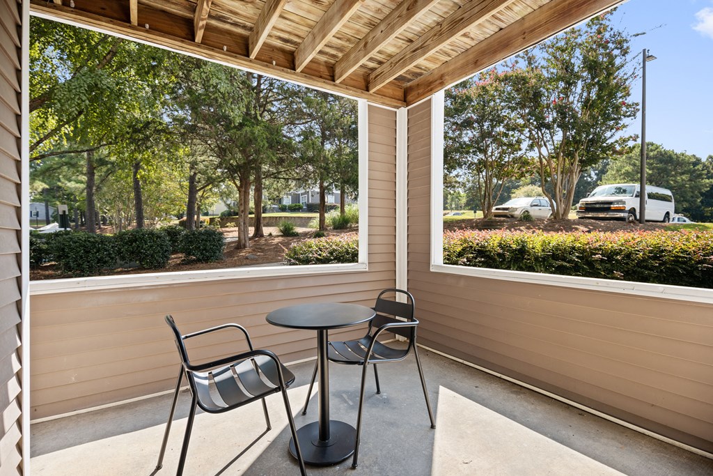 a patio with two chairs and a table in front of a window