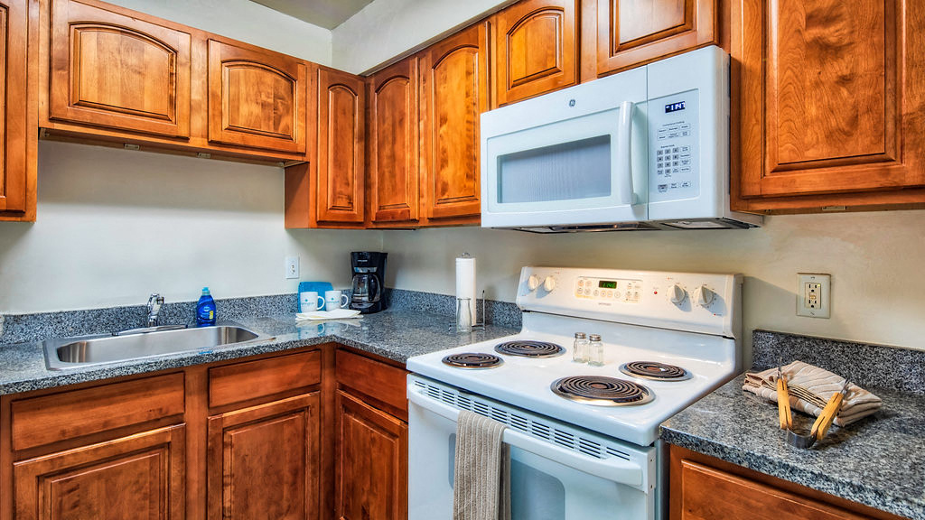 A kitchen with a white stove and wooden cabinets.