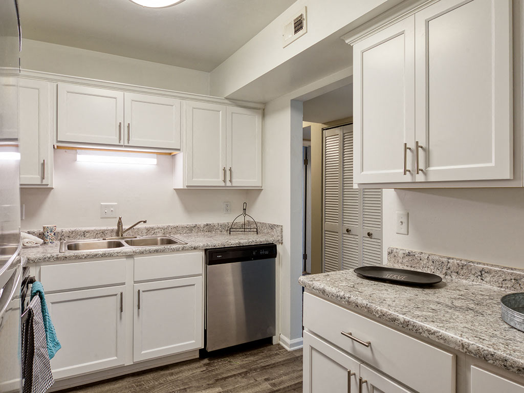 A kitchen with white cabinets and a granite countertop.