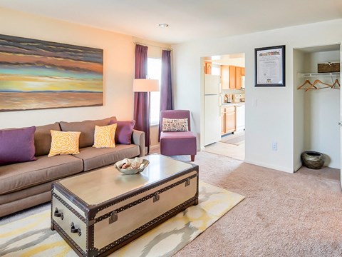 A living room with a brown couch and a painting on the wall.