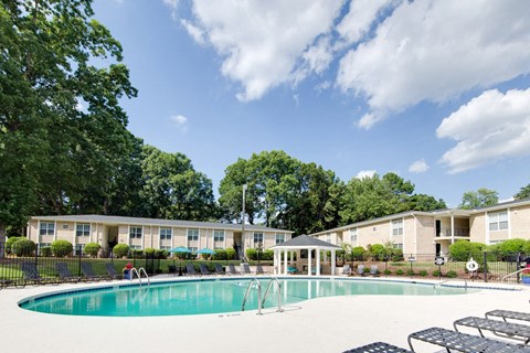 A swimming pool surrounded by trees and a building in the background.