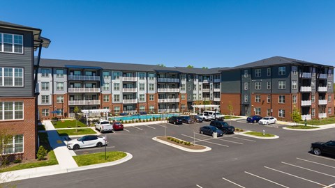 A parking lot in front of a multi-story apartment building.