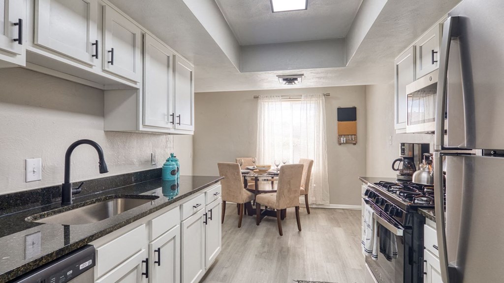 a kitchen with white cabinets and a sink and a table with chairs a kitchen with white cabinets and a sink and a table with chairs at Bayville Apartments, Virginia Beach, VA