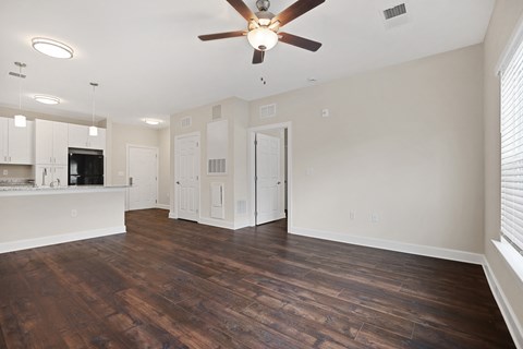 an empty living room with a ceiling fan and a kitchen
