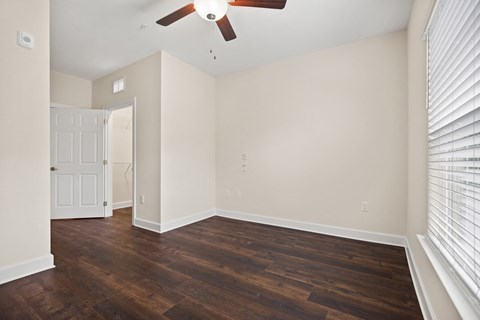 an empty living room with wood floors and a ceiling fan