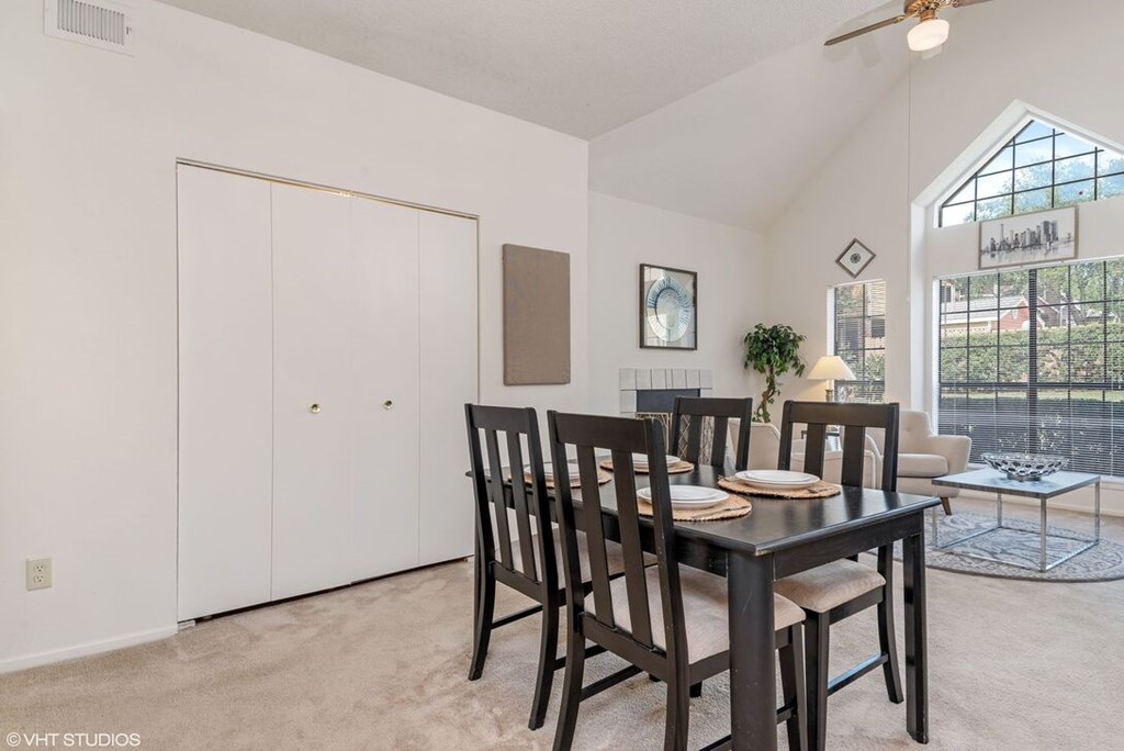 A dining room with a table set for two and a view of the backyard.