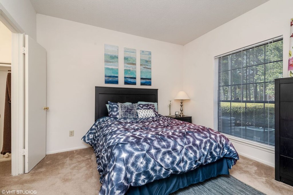A bedroom with a bed, nightstand, and window.